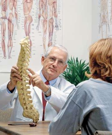 Doctor showing patient spine replica